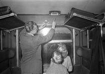 803521 Afbeelding van een vader die zijn kinderen de noodrem en de raamzwengel toont in de coupé van rijtuig van de N.S.